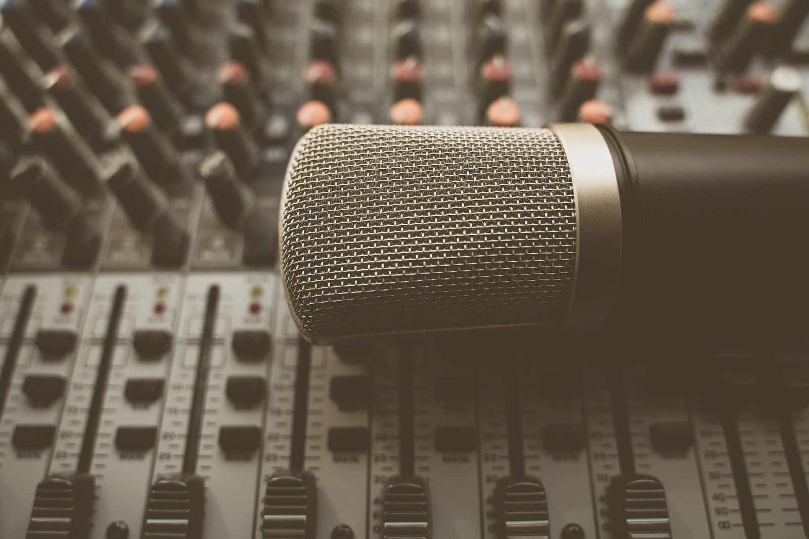 A mic laying on top of a sound mixer.