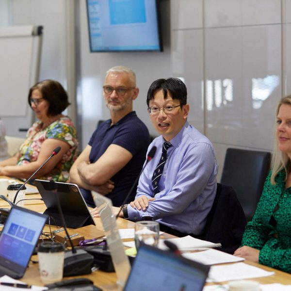 A picture of Bernie Chang chairing a meeting at the RCOphth