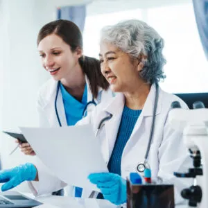 Two scientists in lab coats discussing medical work in a laboratory